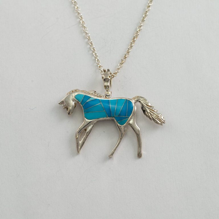This is our reversible horse pendant. It has been cast in Sterling silver and is inlaid on both sides. The chain is silver and is included in the price.