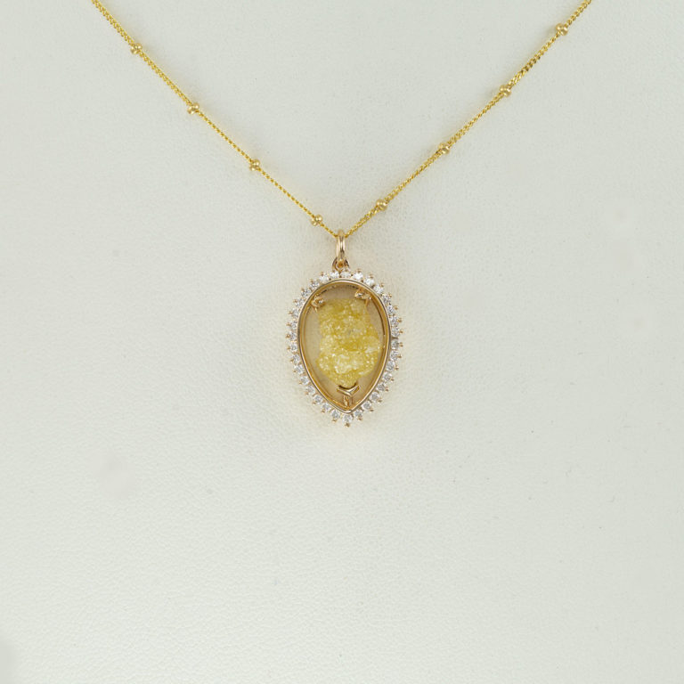 Raw diamond pendant in 14kt yellow gold. Accenting the yellow raw diamond are round, brilliant cut diamonds. The chain is not included.