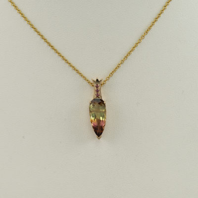This is a pear cut tourmaline pendant. The tourmaline is bi-color and has sapphire accents. The fancy color sapphires and the tourmaline have both been set in 14kt yellow gold. The chain is not included in the price.