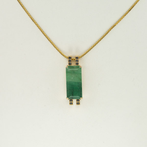 This emerald pendant has black diamond accents. Both the emerald and the diamonds have been set in 14kt yellow gold. The chain is not included in the price.