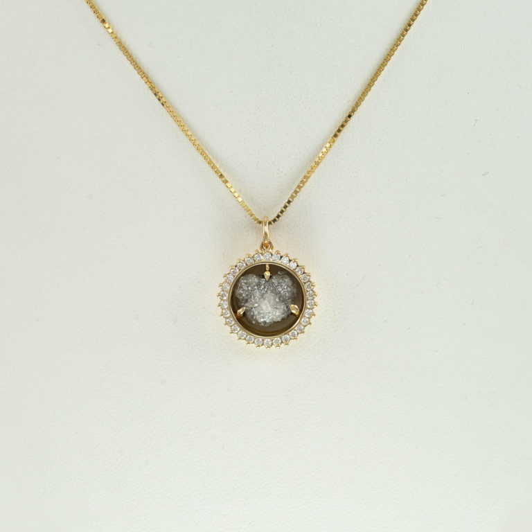 This raw diamond pendant was cast in 14kt yellow gold. Accenting the raw diamond are brilliant-cut, round diamonds. The chain is not included in the price.