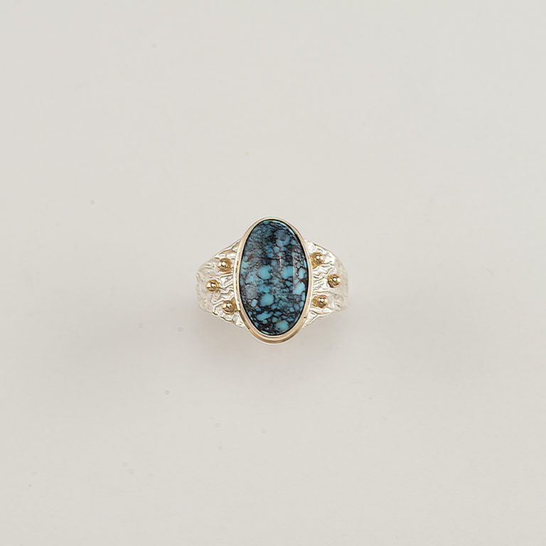 This Men's Turquoise ring has a Sterling Silver ring shank. The bezel is 14kt yellow Gold as well as several gold "BB's".