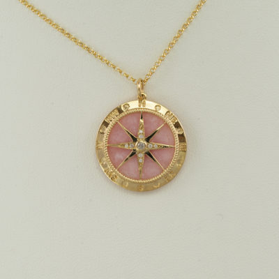 This pink opal compass was set in 14kt yellow gold. Accenting the pink opal are white diamonds. The chain is not included in the price.