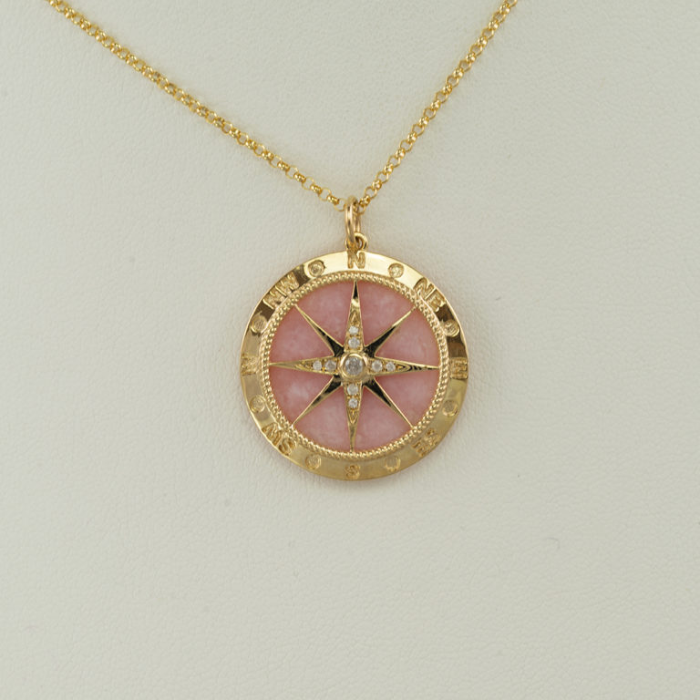 This pink opal compass was set in 14kt yellow gold. Accenting the pink opal are white diamonds. The chain is not included in the price.