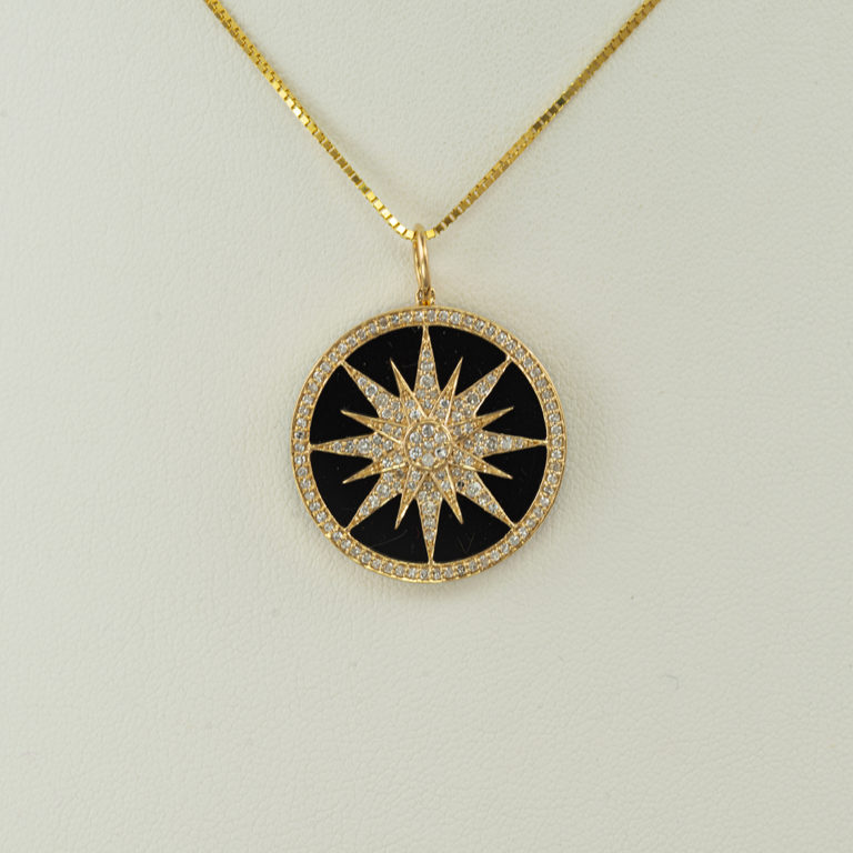 This compass pendant was made with black onyx. Accenting the onyx are white diamonds. Both the onyx and the white diamonds are set in gold.