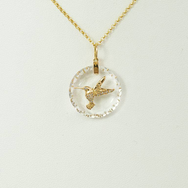This is gold hummingbird pendant. The gold hummingbird has been set with white diamonds over a faceted white quartz. The chain is not included.