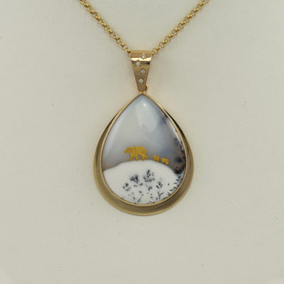 This bear and cub pendant has base of winter agate. The mama bear and cub have been hand-carved with 24kt yellow gold.