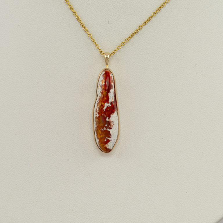 This raw fire opal pendant is one of two. It has been set in 14kt yellow gold with a sterling silver backplate. The chain is not included in the price.