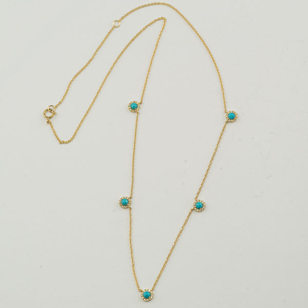 This contemporary turquoise necklace has diamond accents. Both the diamonds and turquoise have been set in 14kt yellow gold.