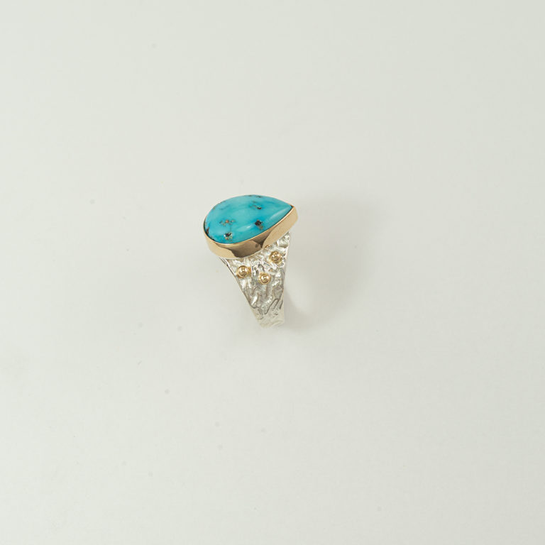 This is a turquoise and silver ring. It has gold accents. The turquoise is from the sleeping beauty mine. Shown in a size 8.25, but can be re-sized.
