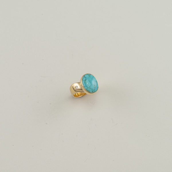 This turquoise ring has diamond accents. Both the turquoise and the diamonds have been set in 14kt yellow gold. Shown in a size 6, but can be re-sized.