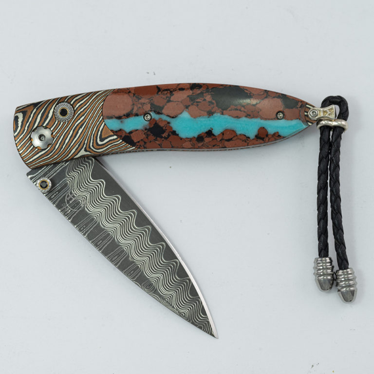 This is the Magma by William Henry. It is 16 of 50 produced. Featuring wave damascus, mokume gane, black spinel and lava rock with turquoise.