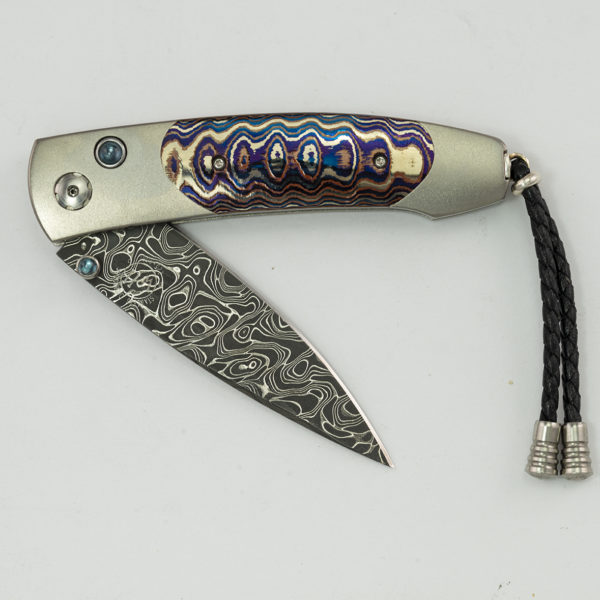 This is the Dark Fire by William Henry. It is 28 of 250 produced. Featuring titanium mokume gane, topaz and intrepid damascus. The blade is B05.