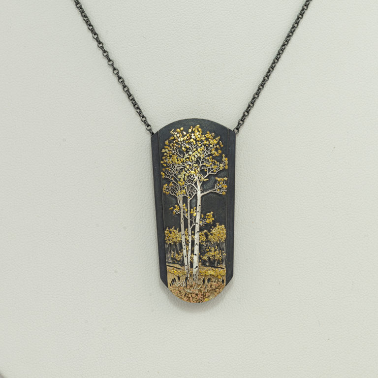 This gold aspen pendant was created by Wolfgang Vaatz. The pendant has a base of sterling silver. The chain is adjustable.