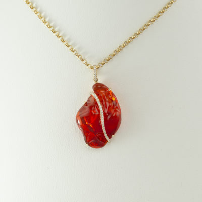 This is a fire opal and diamond pendant. The fire opal is a free form shape accented with diamond. Made with 14kt yellow gold.