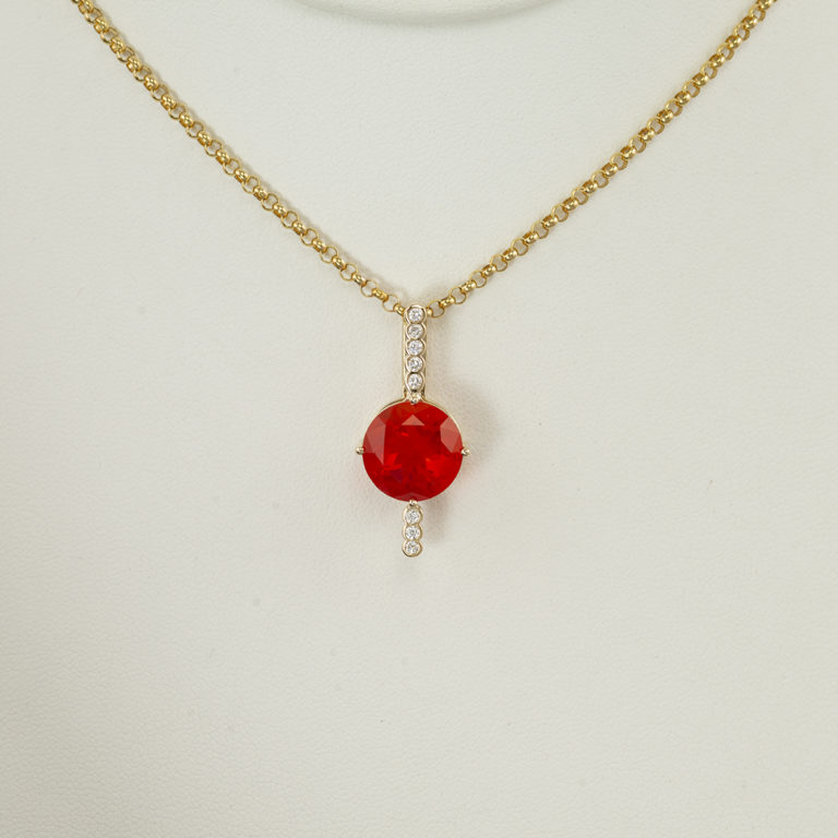 This fire opal pendant has been set in 14kt yellow gold. It has diamond accents and the chain is separately. 