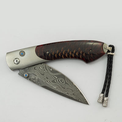 This is the Queensland by William Henry. It features boomerang damascus, titanium, blue topaz and blue spruce pine cone. The blade is a B12.