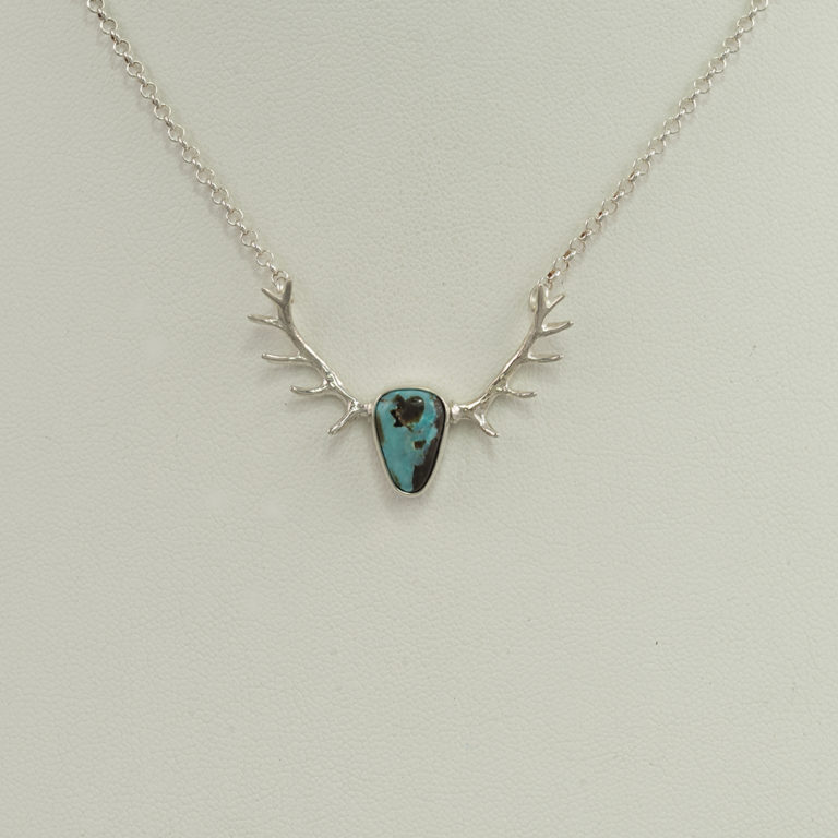 This is a silver and Kingman turquoise pendant. The pendant is part of our antler collection. This pendant features the "smaller" antlers.
