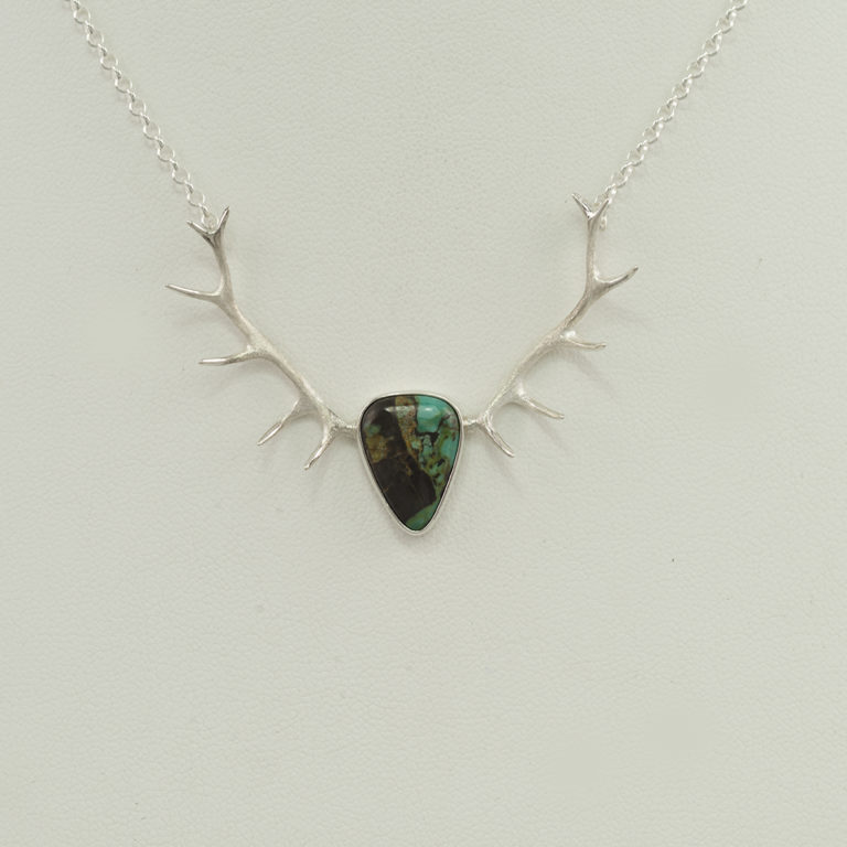 This large antler pendant has a center stone of Carico Lake Turquoise. It measures 18" in length and has lobster claw clasp.