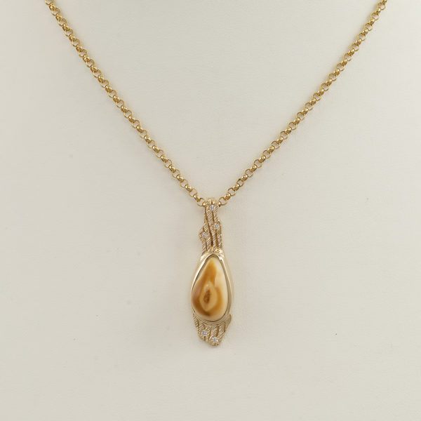 This elk ivory pendant has been made with 14kt yellow gold. Accenting the elk ivory are white diamonds. The chain is sold separately. 