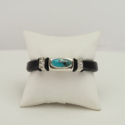 This turquoise bracelet was made with silver, leather and a stainless steel clasp. It is 7.5" in length.