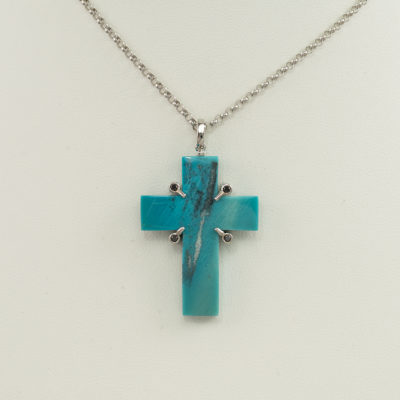 This chrysocolla cross pendant has black diamond accents. Both the chrysocolla and the black diamonds have been set in sterling silver. The silver has been rhodium plated. It comes with either a silver chain, at no extra charge, or a white gold chain, which would have an additional cost.
