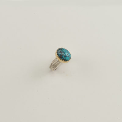 Here is a ladies turquoise and silver ring. The turquoise has been bezel set in 14kt yellow gold. The ring shank was cast in sterling silver. Shown in a size 7.25, but can be re-sized.