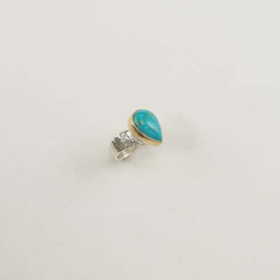 This ladies Kingman turquoise ring has a gold bezel. The ring shank was made with sterling silver. Shown in a size 6.5, but can be re-sized.