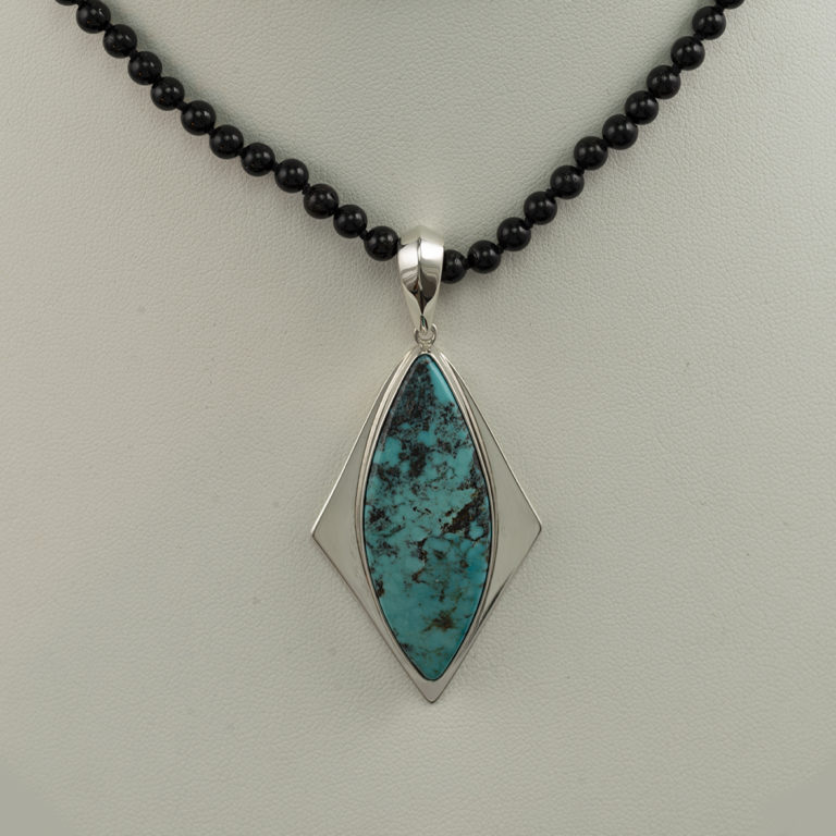 This blue turquoise pendant has been set in silver. The turquoise is from Nevada and the black tourmaline beads are sold separately.