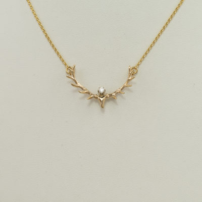 This antler and Diamond pendant was cast in 14kt yellow gold. There is a round, brilliant cut diamond in the center. The diamond is .10ct in weight. The chain is included in the price.