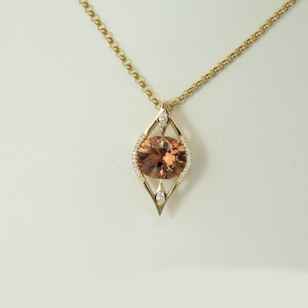 Here is a peach tourmaline pendant with diamond accents in 18kt. The peach tourmaline is an oval cut and the diamonds are brilliant cut.