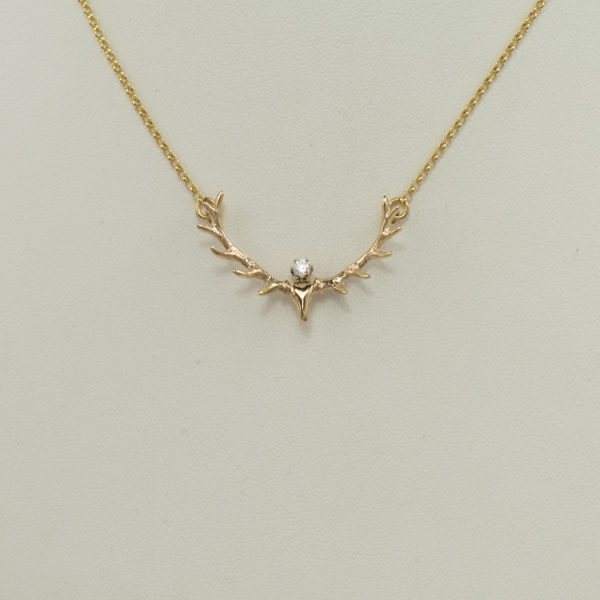 This small antler pendant has a diamond accent. The piece was cast in 14kt yellow gold and the diamond is a white, round cut.