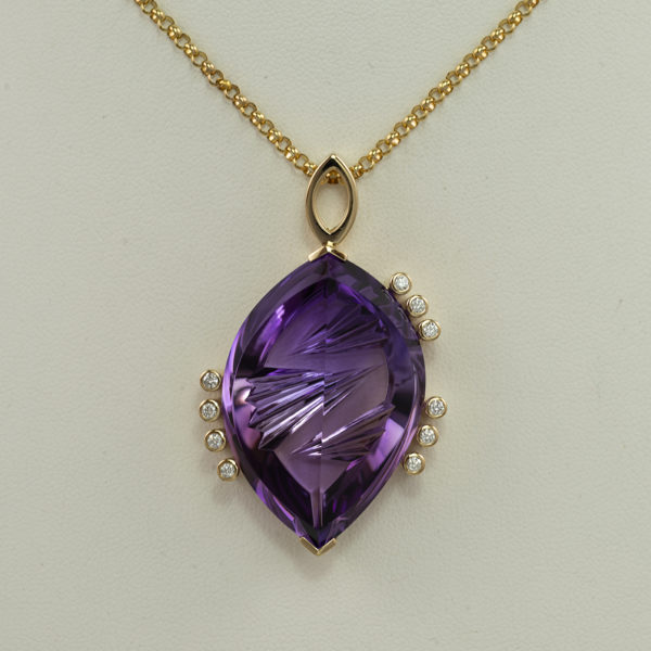 This fantasy cut Amethyst has diamond accents. Both the Amethyst and the Diamonds have been set in 14kt yellow gold. The chain is not included in the price.