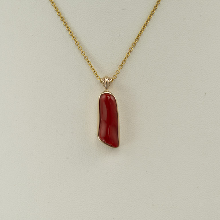 Here is a red coral pendant with a gold bail and bezel. The backplate is sterling silver. The chain is sold separately. 