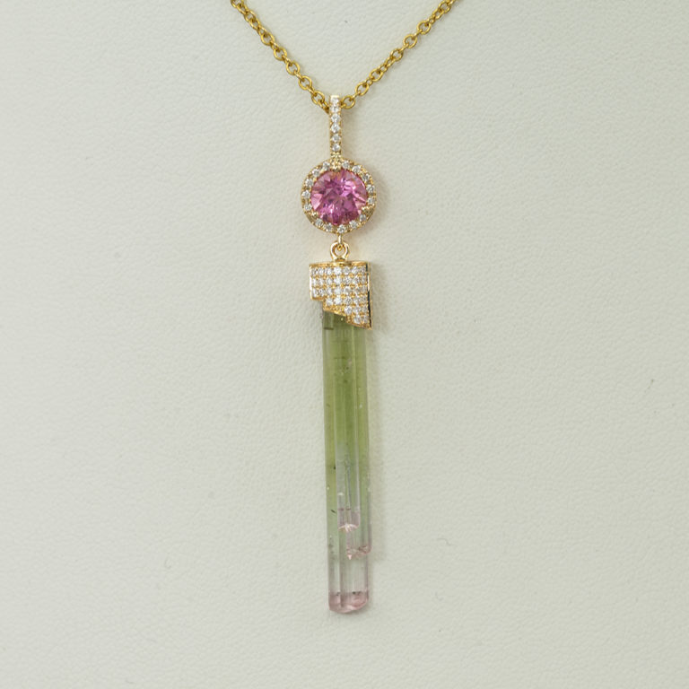 This tourmaline crystal pendant has diamond accents. Both the diamonds and the tourmaline have been set in 14kt yellow gold.