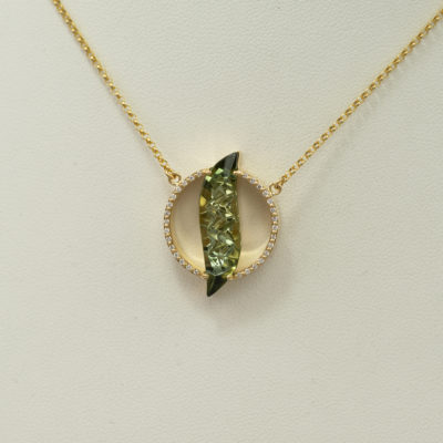 This green tourmaline pendant was cast in 18kt yellow gold. Accenting the tourmaline are white diamonds. The tourmaline was cut by Alexander Kreis.