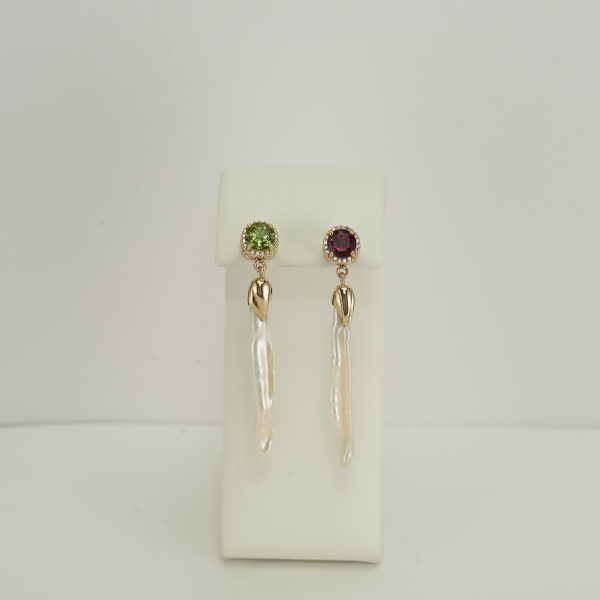 These long pearl earrings have been set in 14kt yellow gold. Our designer has used green and pink tourmaline along with diamonds to accent the pearls. The pearls are fresh water. These are one of a kind. 