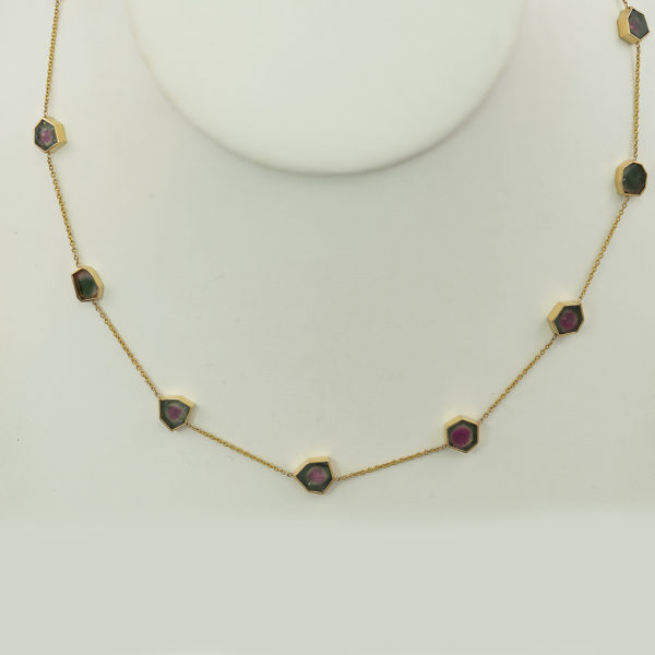 This watermelon tourmaline necklace is adjustable in length. It has been made with 18kt yellow gold and has a lobster claw clasp. The watermelon tourmaline have been cut into slices and then cut into hexagons. 