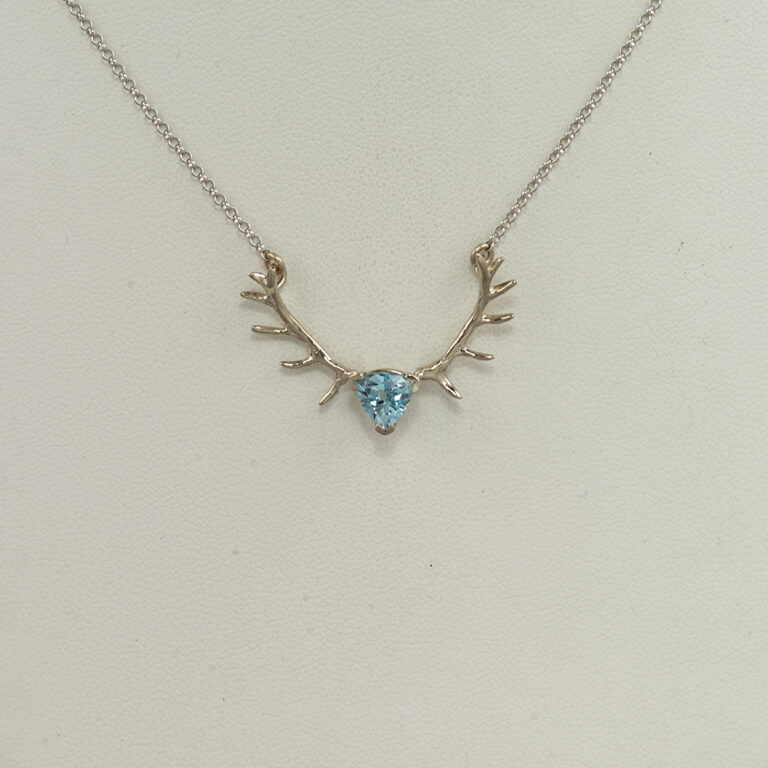 This is the small aquamarine antler pendant in white gold. The white gold is 14kt. The aquamarine is trillion cut and has a very deep, saturated color. We also have a larger version as well. The chain has a lobster claw clasp and is included in the price.