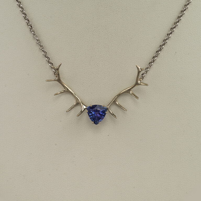 This Tanzanite antler pendant has been set in 14kt white gold. The tanzanite is a trillion cut and has much more purple than the picture indicates.
