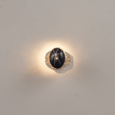 Here is a star sapphire ring for men. The star sapphire is blue. It has been set in a 14kt yellow gold and solid sterling silver.