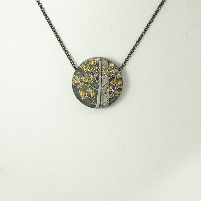 This aspen tree pendant was hand made by Wolfgang Vaatz. The tree bark was made from argentium silver and the leaves are made from placer gold. The chain is adjustable and included in the price.