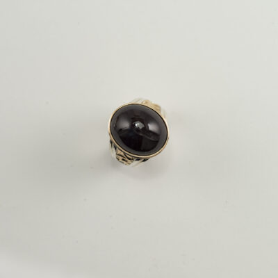 This men's sapphire ring has sterling silver and 14kt yellow gold. The sapphire is a black star cabochon. Shown in a size 10.75, but can be re-sized.