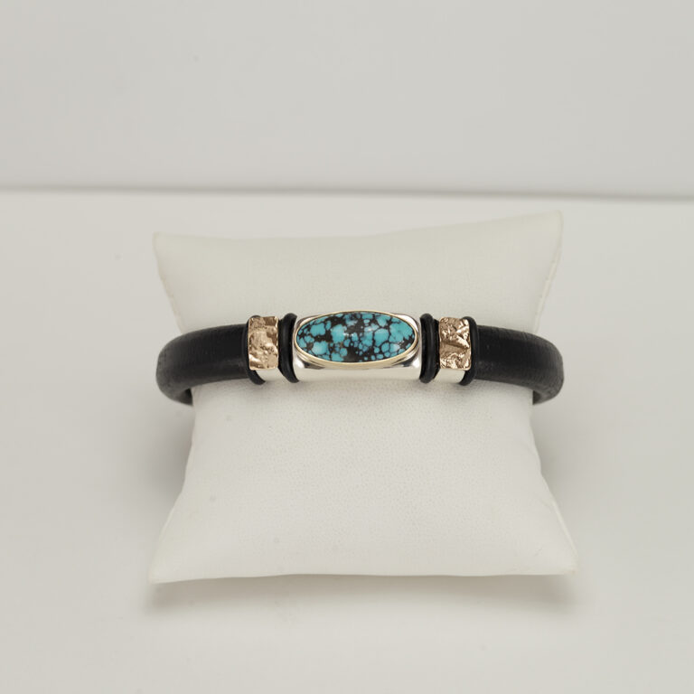 Here is a turquoise and leather bracelet. The hubei turquoise has been accented with 14kt yellow gold and sterling silver. The leather is black.