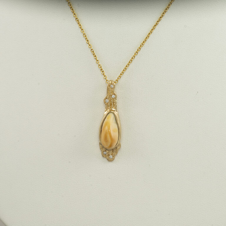 This bull ivory pendant was made with yellow gold. The gold is 14kt and has diamond accents. The diamonds have been flush set into gold.