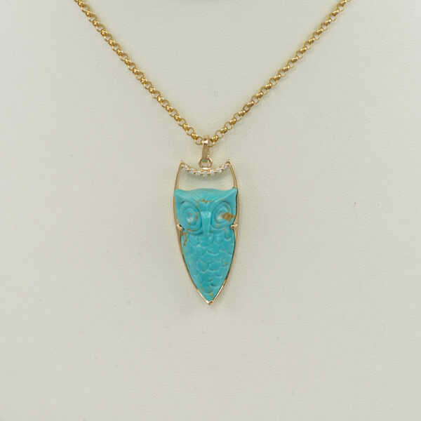 Here is a carved turquoise owl. It has been set in 14kt yellow gold. Accenting the turquoise owl are brilliant cut diamonds. Chain not included.