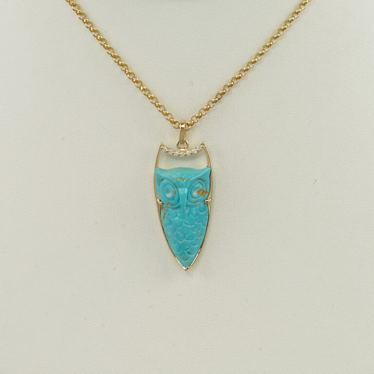 Here is a carved turquoise owl. It has been set in 14kt yellow gold. Accenting the turquoise owl are brilliant cut diamonds. Chain not included.