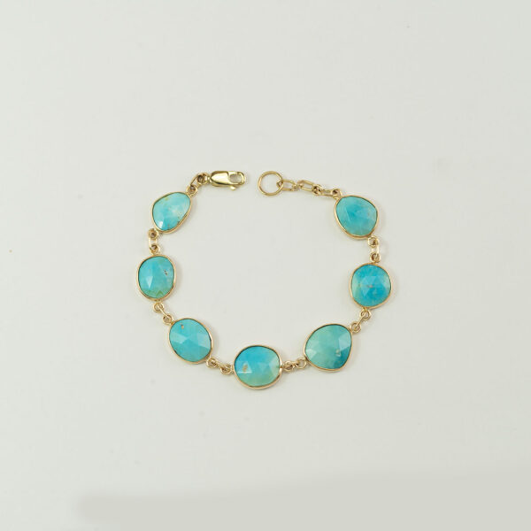 This turquoise bracelet in gold is one-of-a-kind. The turquoise has been top-faceted. The gold is 14kt. Shown in a size 7.