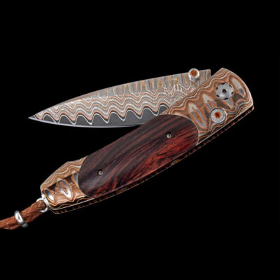 The Monarch 'Scorch' features a handle in 'Wave' mokume gane, inlaid with cocobolo wood. The blade is 'Copper Wave' damascus steel with a core in VG-5 steel