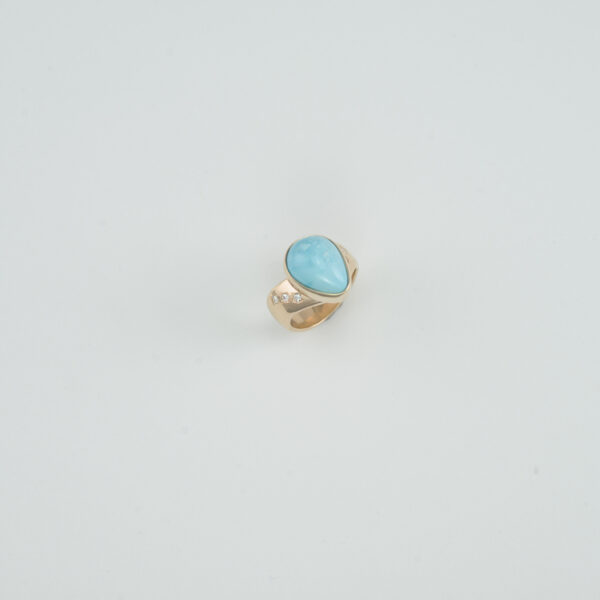 This Kingman turquoise ring has diamond accents. The Kingman turquoise is a pear cut and the diamonds are round, brilliant cut. All the stones have been set in 14kt yellow gold. Shown in a size 6.